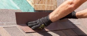 Roofing contractor installing brown asphalt shingles